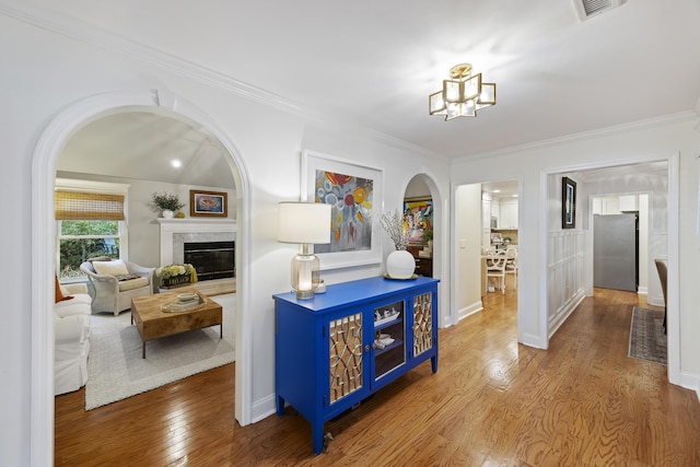 hallway with hardwood / wood-style floors, an inviting chandelier, and ornamental molding