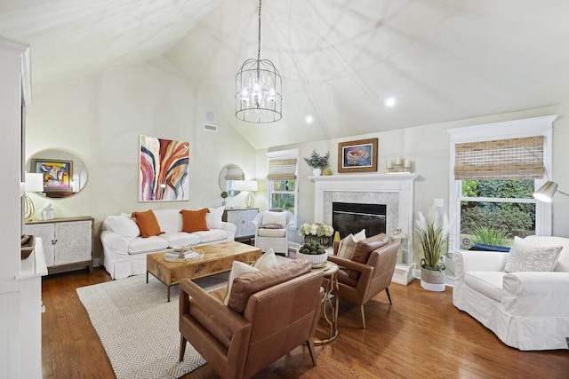 living room with a fireplace, dark hardwood / wood-style flooring, an inviting chandelier, and vaulted ceiling