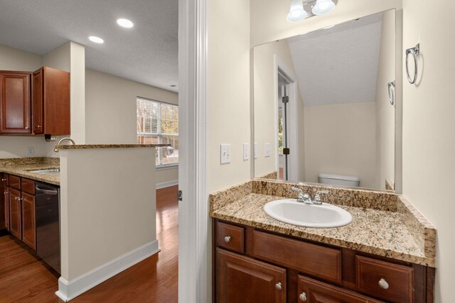 bathroom featuring hardwood / wood-style floors, vanity, lofted ceiling, toilet, and a textured ceiling