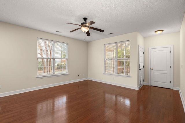 unfurnished room with a textured ceiling, a wealth of natural light, and dark hardwood / wood-style floors