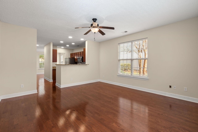 unfurnished living room with ceiling fan, dark wood-type flooring, and a textured ceiling