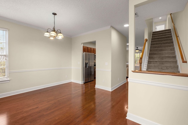 empty room with crown molding, ceiling fan with notable chandelier, dark hardwood / wood-style floors, and a textured ceiling