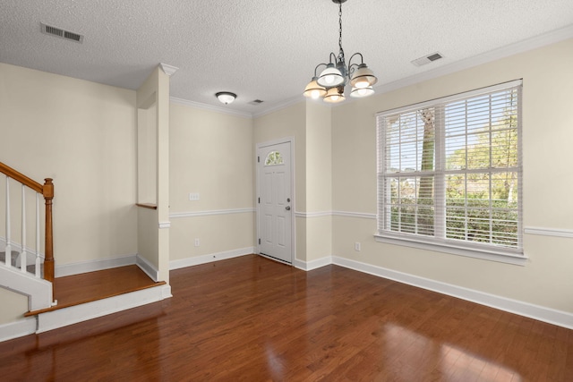 interior space featuring a textured ceiling, a chandelier, dark hardwood / wood-style floors, and ornamental molding