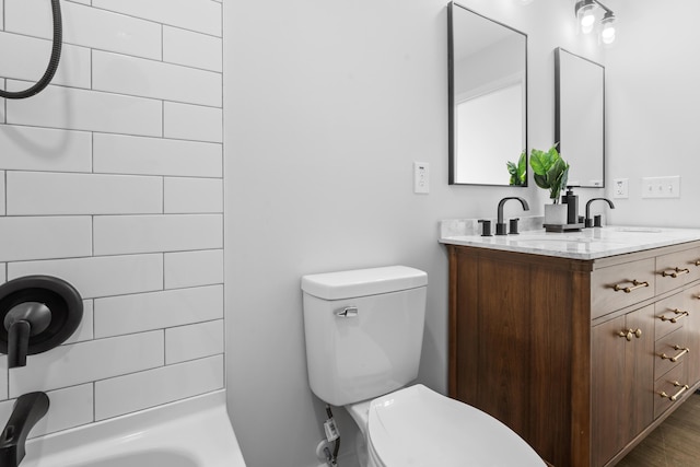 bathroom with a tile shower, vanity, and toilet