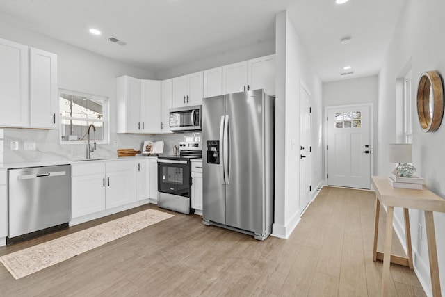 kitchen with backsplash, white cabinetry, sink, and appliances with stainless steel finishes