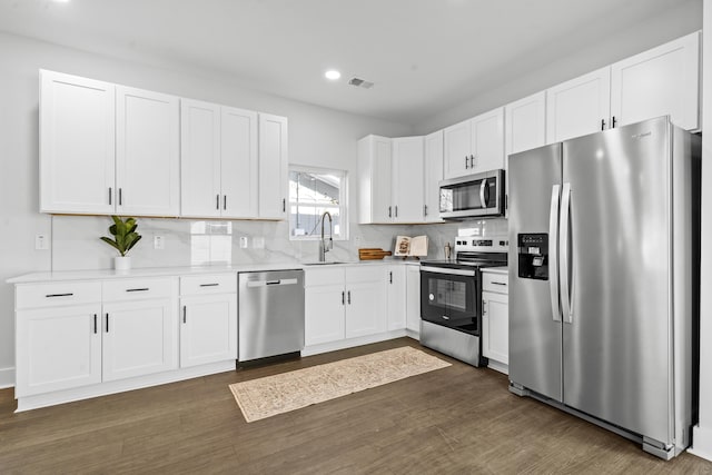 kitchen featuring appliances with stainless steel finishes, tasteful backsplash, white cabinetry, and sink