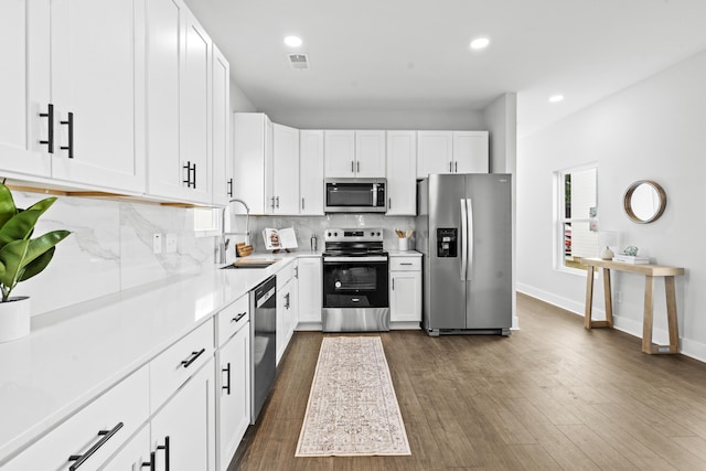 kitchen with sink, tasteful backsplash, dark hardwood / wood-style floors, white cabinets, and appliances with stainless steel finishes