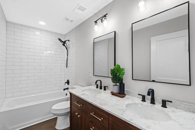 full bathroom with vanity, tiled shower / bath combo, hardwood / wood-style flooring, and toilet