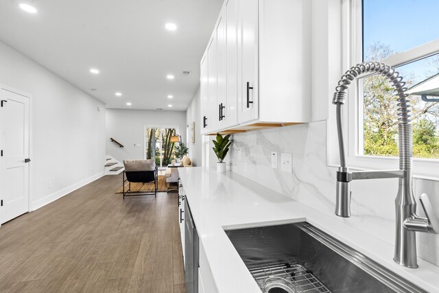 kitchen featuring sink, dark hardwood / wood-style flooring, white cabinetry, and backsplash