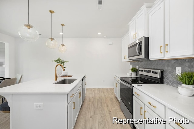 kitchen featuring white cabinets, appliances with stainless steel finishes, a breakfast bar, hanging light fixtures, and a sink