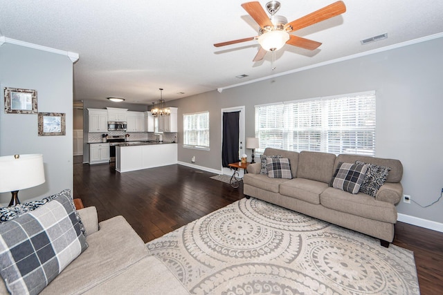 living room featuring ceiling fan with notable chandelier, a textured ceiling, ornamental molding, and dark hardwood / wood-style floors