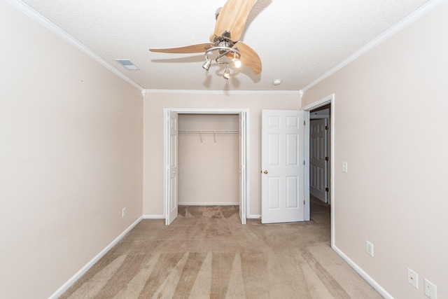 unfurnished bedroom with a closet, light carpet, crown molding, ceiling fan, and a textured ceiling