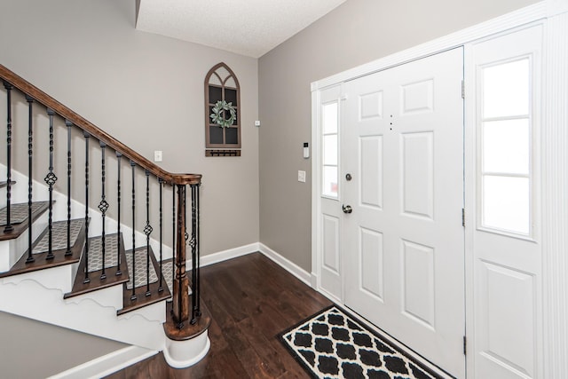 foyer entrance with a textured ceiling and dark wood-type flooring