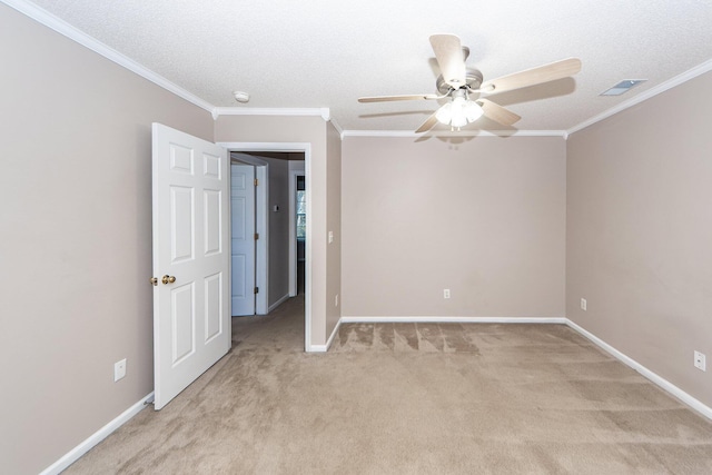 carpeted spare room with a textured ceiling, ceiling fan, and crown molding