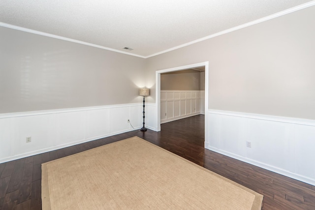 empty room with dark wood-type flooring, a textured ceiling, and ornamental molding