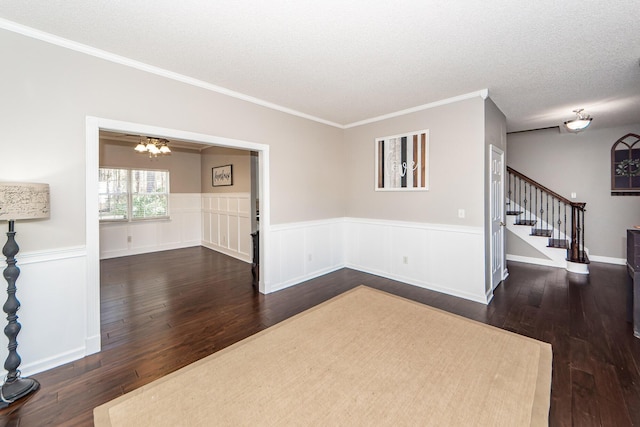 empty room with a textured ceiling, an inviting chandelier, crown molding, and dark hardwood / wood-style floors