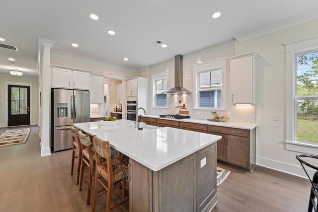 4235 Royal Harbor Rd, Hollywood, SC 29449 - kitchen featuring backsplash, visible vents, wall chimney exhaust hood, a center island with sink, and appliances with stainless steel finishes