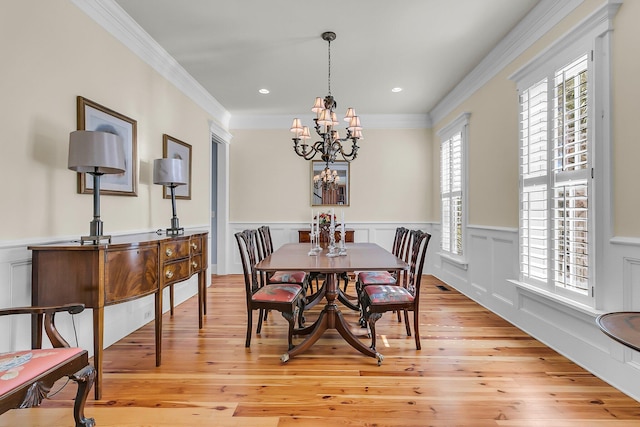 dining area with visible vents, a chandelier, ornamental molding, wainscoting, and light wood-style floors