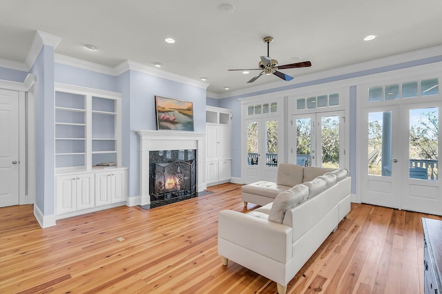 living area with light wood-type flooring, recessed lighting, french doors, crown molding, and a premium fireplace