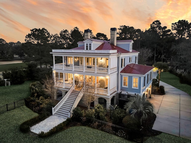 rear view of property featuring a balcony, stairway, fence, driveway, and covered porch