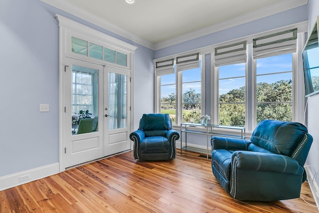 sitting room with french doors, baseboards, light wood-style floors, and ornamental molding