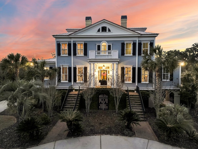 view of front of property with stairs, a balcony, a standing seam roof, and metal roof