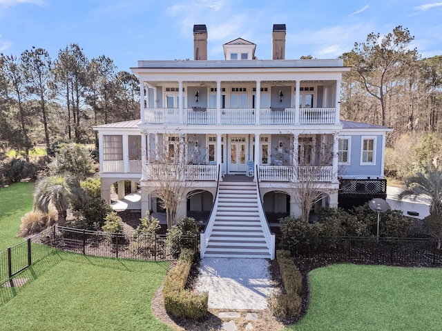 view of front of home with stairway, a balcony, french doors, and a front lawn