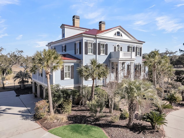 view of front of property featuring a balcony, concrete driveway, and a chimney