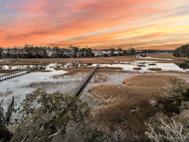 yard at dusk featuring a water view