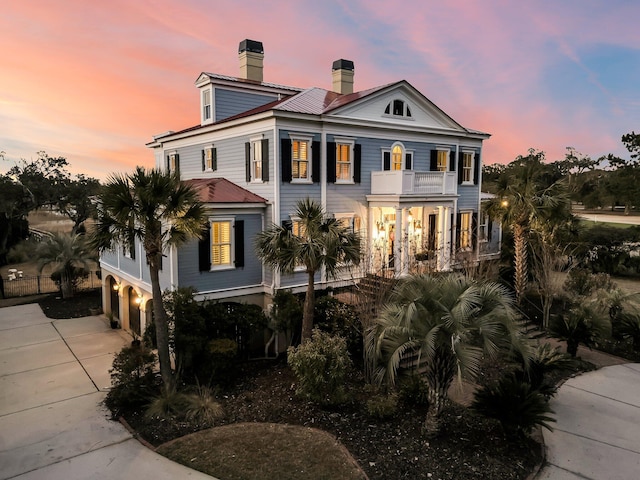 view of front of property featuring concrete driveway, a balcony, a garage, and a chimney