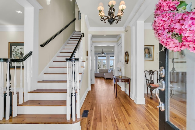 foyer with visible vents, crown molding, light wood finished floors, baseboards, and stairs