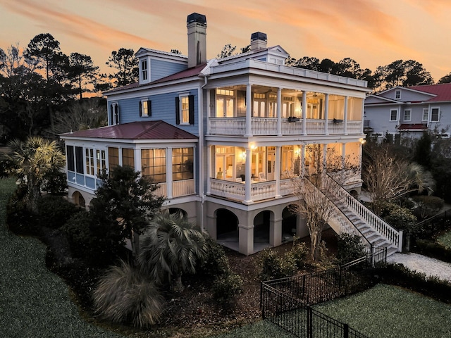 back of house featuring a chimney, stairs, and a balcony