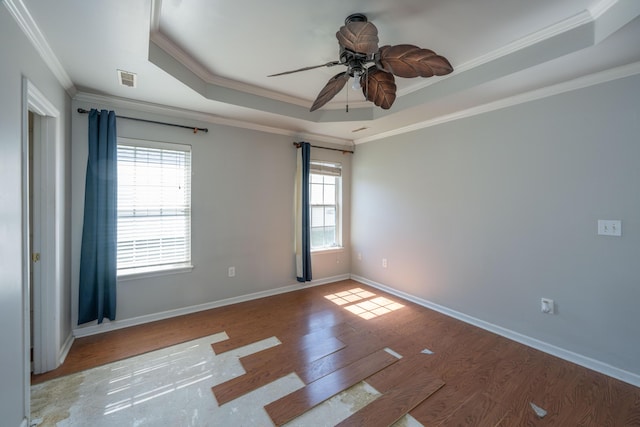 unfurnished room featuring visible vents, baseboards, a raised ceiling, wood finished floors, and crown molding