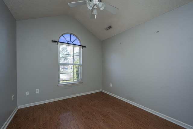 spare room featuring dark wood finished floors, lofted ceiling, visible vents, a textured ceiling, and baseboards