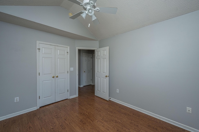 unfurnished bedroom with a closet, vaulted ceiling, baseboards, and wood finished floors