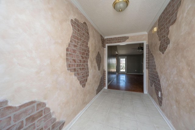 corridor featuring a textured ceiling, ornamental molding, tile patterned floors, and baseboards