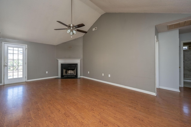 unfurnished living room with a fireplace with flush hearth, visible vents, vaulted ceiling, and wood finished floors