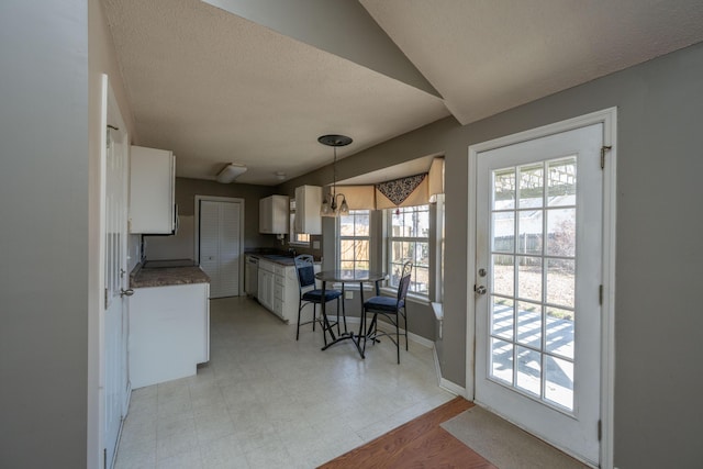 kitchen featuring light floors, dark countertops, white cabinets, a textured ceiling, and baseboards