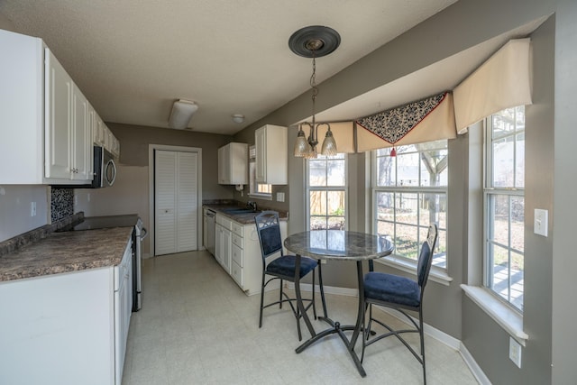 kitchen featuring light floors, appliances with stainless steel finishes, dark countertops, and white cabinets