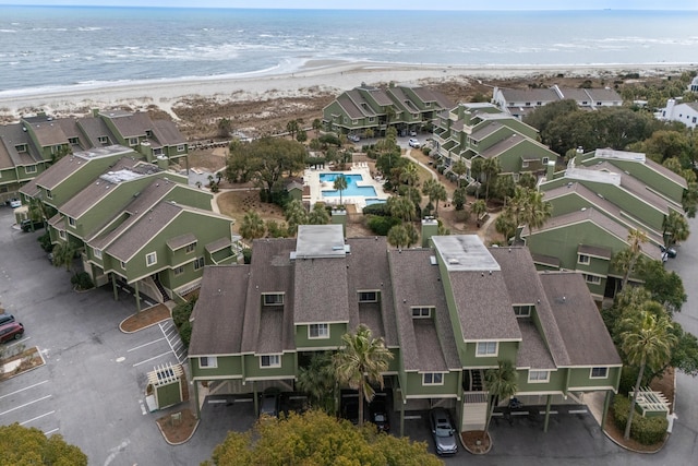 drone / aerial view featuring a water view, a view of the beach, and a residential view