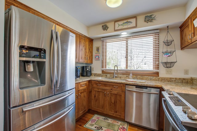 kitchen with stainless steel appliances, a sink, and brown cabinets