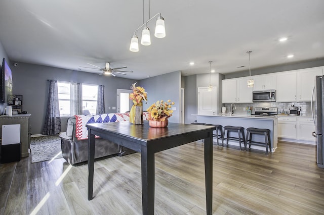 dining area featuring ceiling fan, sink, and light hardwood / wood-style flooring