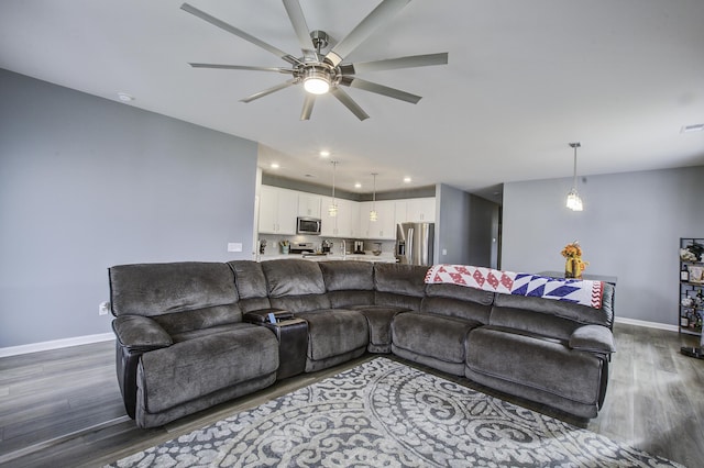 living room featuring ceiling fan and dark hardwood / wood-style floors