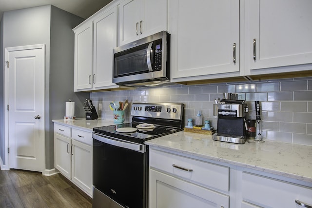 kitchen with light stone countertops, white cabinetry, stainless steel appliances, dark hardwood / wood-style floors, and decorative backsplash