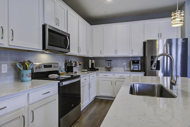 kitchen featuring tasteful backsplash, light stone counters, stainless steel appliances, sink, and white cabinetry