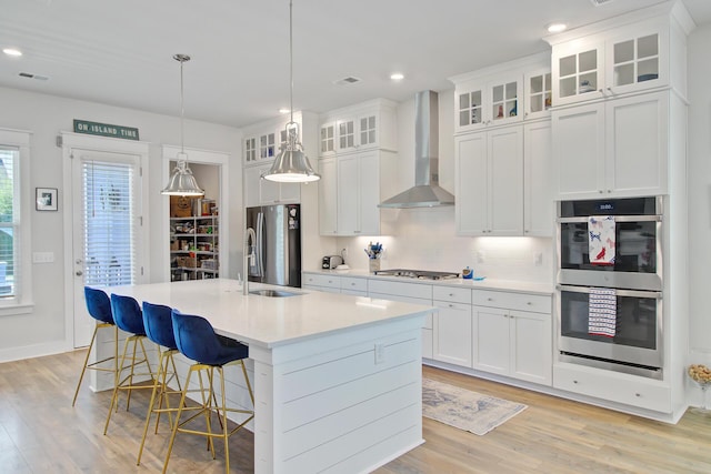 2557 Hatch Dr, Johns Island, SC 29455 - kitchen with wall chimney range hood, a sink, light wood-style flooring, stainless steel appliances, and decorative backsplash
