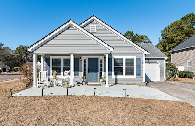 view of front of home featuring a front yard, covered porch, and a garage