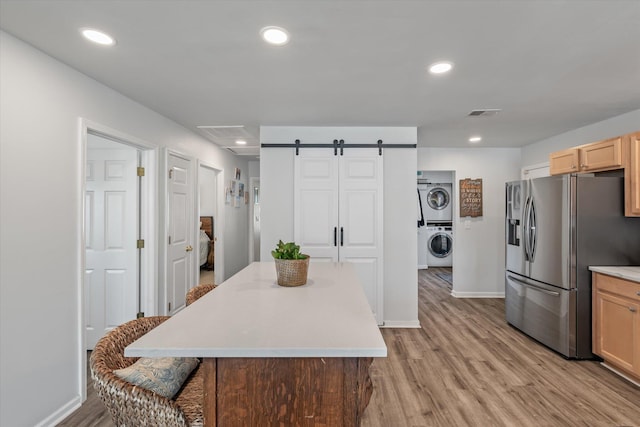 kitchen featuring stacked washing maching and dryer, a barn door, stainless steel fridge, and a center island