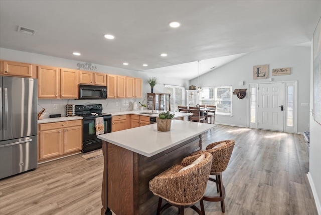 kitchen with a breakfast bar area, backsplash, light brown cabinetry, lofted ceiling, and black appliances