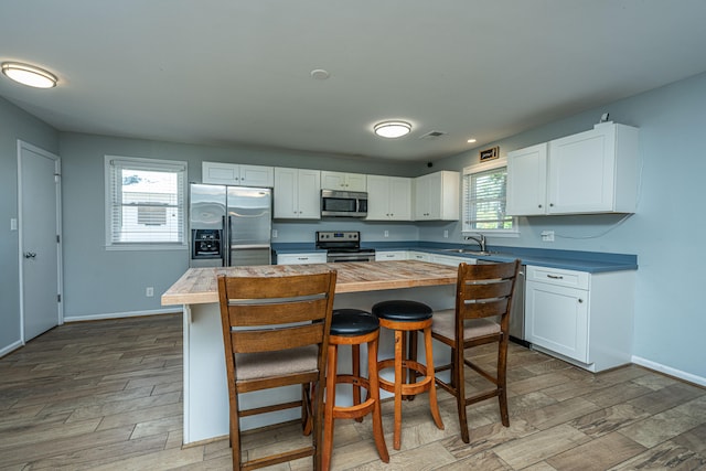 kitchen with a kitchen island, white cabinetry, stainless steel appliances, and plenty of natural light